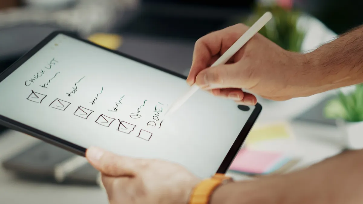 Content standards and editorial process — The Complete Guide Hand checking boxes on a tablet checklist